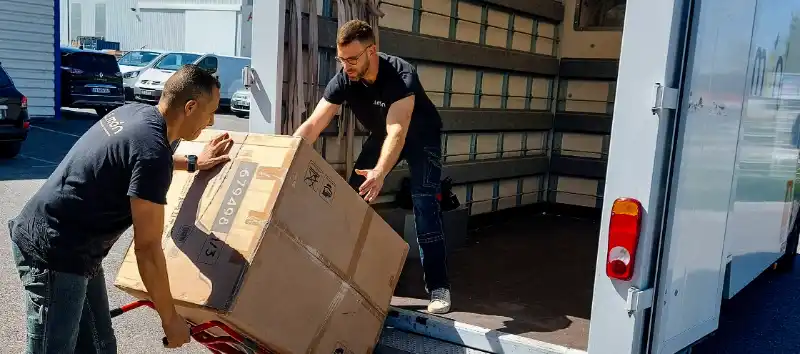 2 livreur-monteurs déchargent un colis volumineux du camion